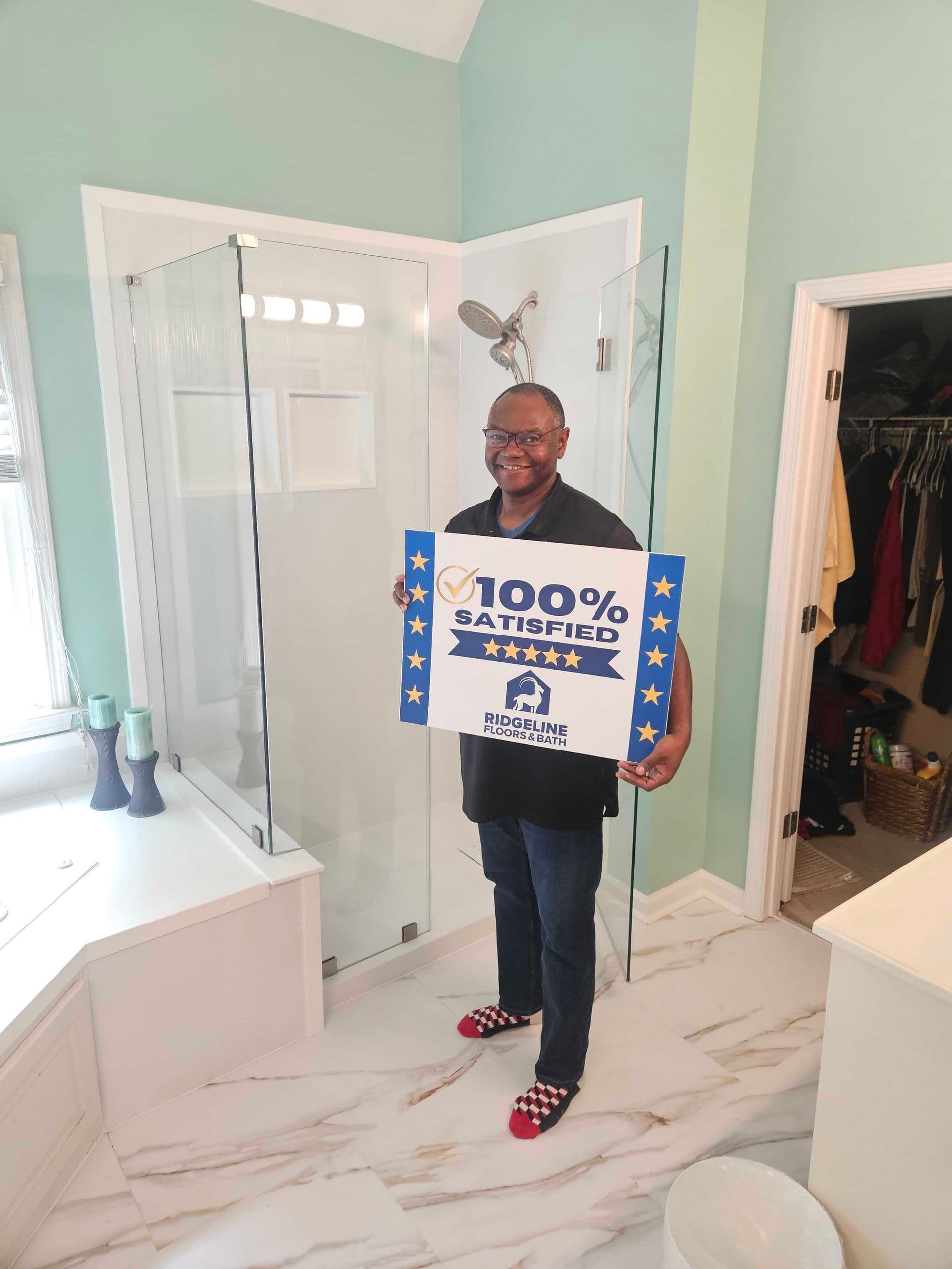 Man holding 100% satisfied customer review sign in modern bathroom with glass shower enclosure and mint green walls